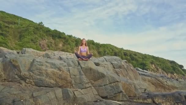 Meisje doet yoga op rotsachtige Oceaan kust — Stockvideo