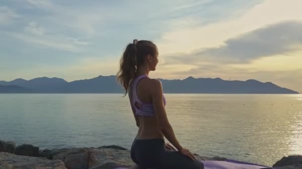 Chica haciendo yoga en la costa rocosa del océano — Vídeo de stock