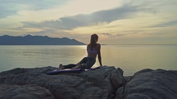 Girl doing yoga on rocky ocean coast — Stock Video