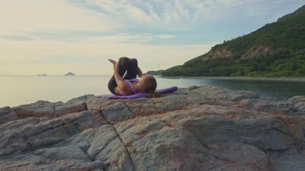 Girl doing yoga on rocky ocean coast — Stock Video