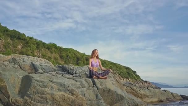 Holka dělá jógu na pobřeží skalnaté oceánu — Stock video