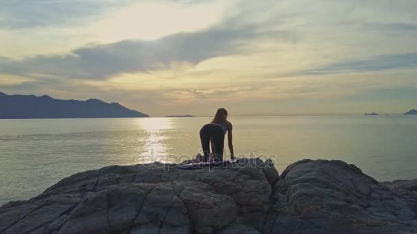 Mädchen beim Yoga an der felsigen Küste des Ozeans — Stockvideo