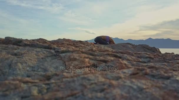 Holka dělá jógu na pobřeží skalnaté oceánu — Stock video