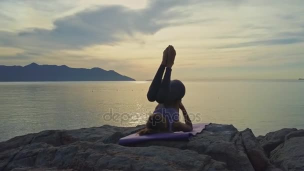 Flicka gör yoga på rocky havet kusten — Stockvideo