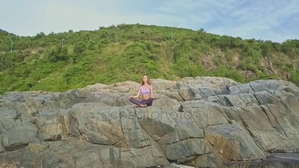 Menina fazendo ioga na costa rochosa do oceano — Vídeo de Stock