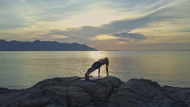 Meisje doet yoga op rotsachtige Oceaan kust — Stockvideo