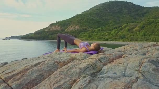 Meisje doet yoga op rotsachtige Oceaan kust — Stockvideo