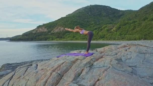 Meisje doet yoga op rotsachtige Oceaan kust — Stockvideo