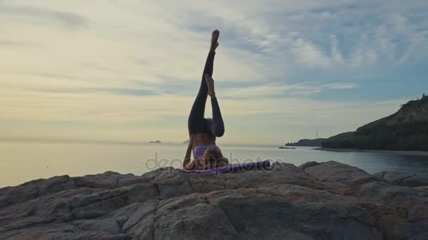 Flicka gör yoga på rocky havet kusten — Stockvideo