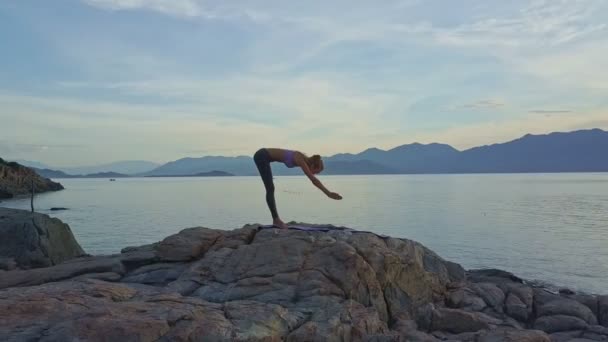 Chica haciendo yoga en la costa rocosa del océano — Vídeo de stock