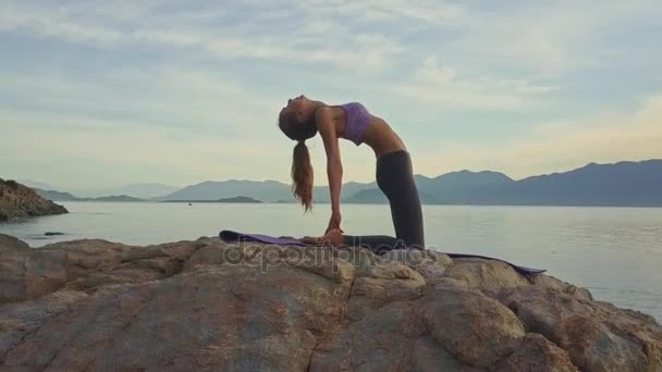 Mädchen beim Yoga an der felsigen Küste des Ozeans — Stockvideo