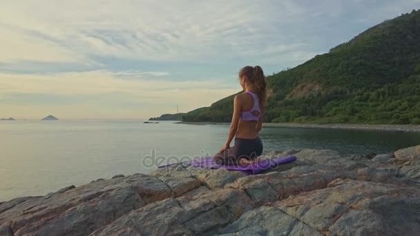 Chica haciendo yoga en la costa rocosa del océano — Vídeos de Stock