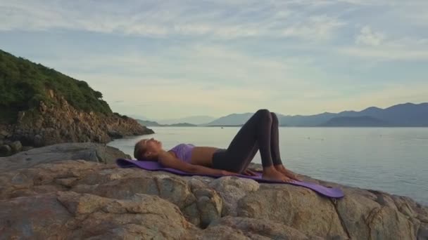 Flicka gör yoga på rocky havet kusten — Stockvideo