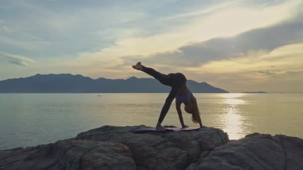 Meisje doet yoga op rotsachtige Oceaan kust — Stockvideo