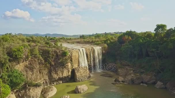 Водопад, впадающий в реку против растений — стоковое видео