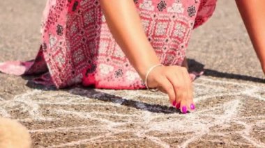 kadın tebeşir resimle asfaltta çizer.