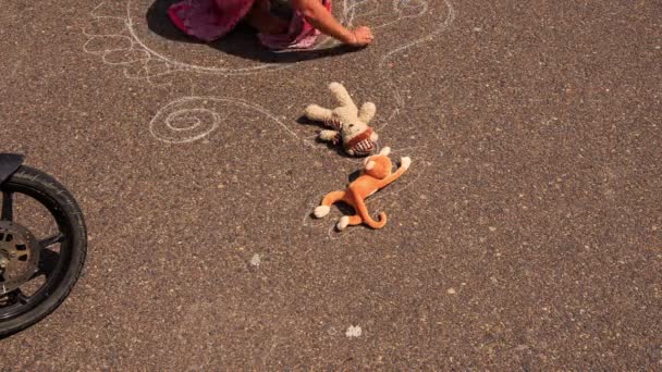 Woman takes away toys from asphalt — Stock Video