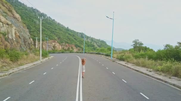 Chica camina a lo largo de carretera vacía — Vídeos de Stock