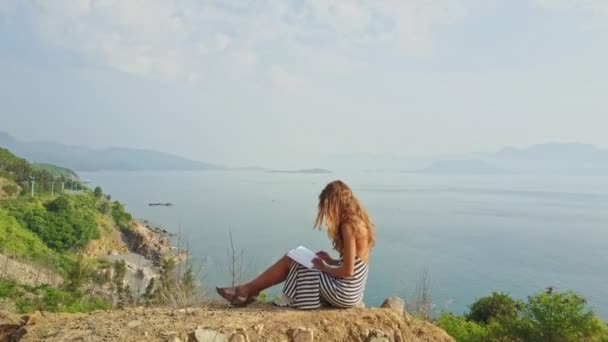 Chica sentada en la cima de la colina y leer libro — Vídeos de Stock
