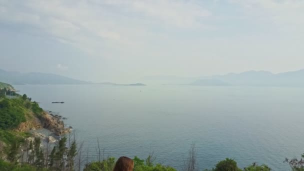 Chica estirándose en la cima de la colina contra el mar y las montañas — Vídeos de Stock