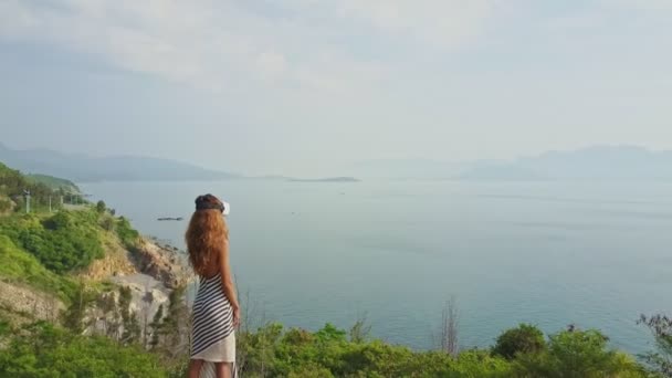Девушка в шлеме виртуальной реальности смотрит на морской пейзаж — стоковое видео