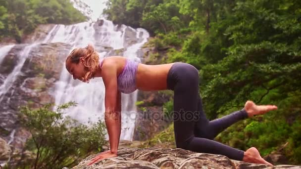 Kvinnan gör yoga nära waterfall — Stockvideo