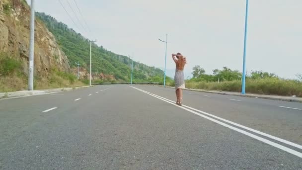 Meisje wandelingen langs lege snelweg — Stockvideo