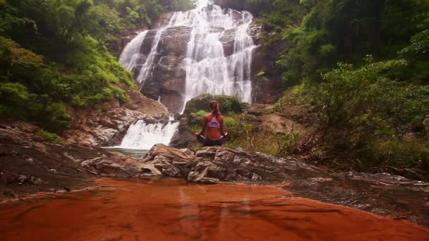 Kvinnan gör yoga nära waterfall — Stockvideo