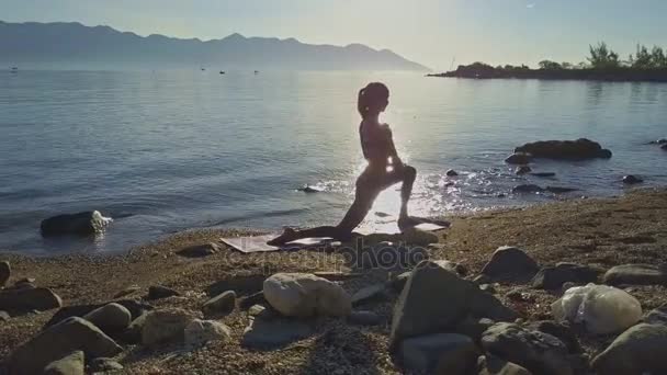 Meisje doet yoga op het strand kust — Stockvideo