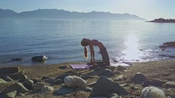 Meisje doet yoga op het strand kust — Stockvideo