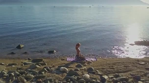 Meisje doet yoga op het strand kust — Stockvideo