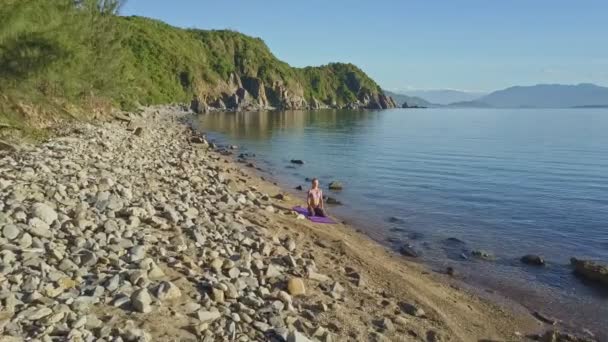 Meisje doet yoga op het strand kust — Stockvideo