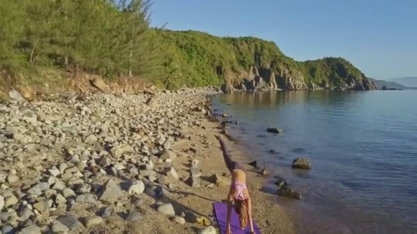Meisje doet yoga op het strand kust — Stockvideo