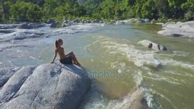 taş river rapids arasında oturan kız