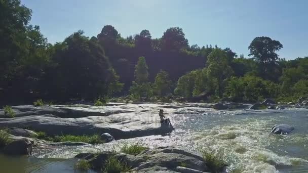 Girl sitting on stone among river rapids — Stock Video