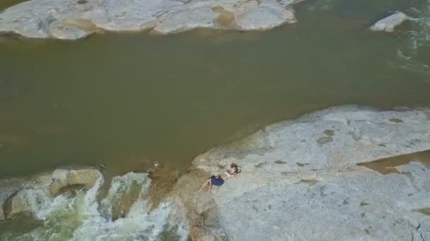 Chica acostada en piedra grande en el río — Vídeos de Stock