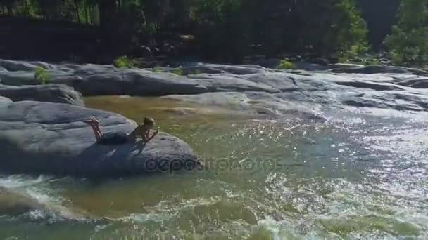 川の急流の中で石の上に横たわる少女 — ストック動画