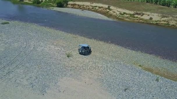 Militär jeep körning på grus nära floden — Stockvideo