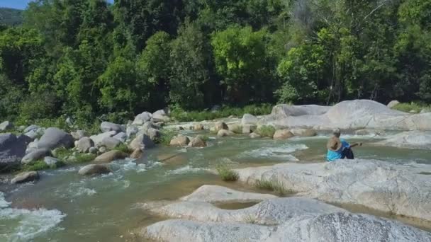 Hombre en piedra pesca en el río de montaña — Vídeo de stock