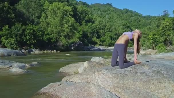 Meisje doet yoga op stenen rivier bank — Stockvideo