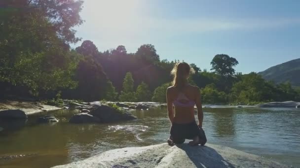 Mädchen macht Yoga am steinernen Flussufer — Stockvideo