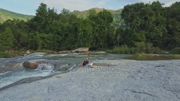 Girl sitting on stone among streaming rive — Stock Video