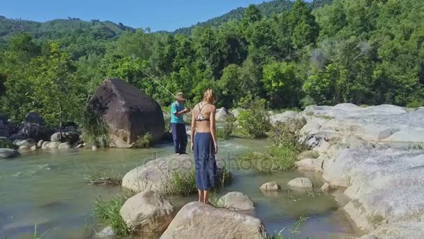 Ragazza guardando come uomo pesca nel fiume — Video Stock