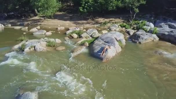 Girl lying on stone among river rapids — Stock Video