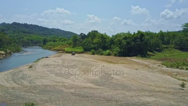 Military jeep driving on gravel near river — Stock Video