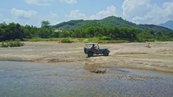 川の近くの砂利で運転軍用ジープ — ストック動画