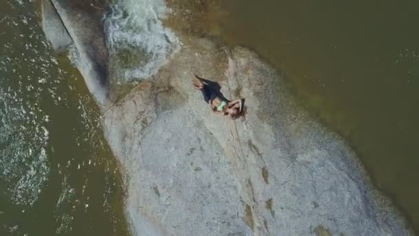 Meisje liggend op een grote steen in rivier — Stockvideo