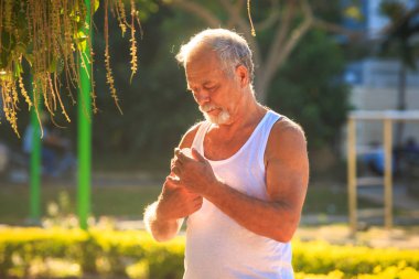 Adam su şişesi parkta tutar.