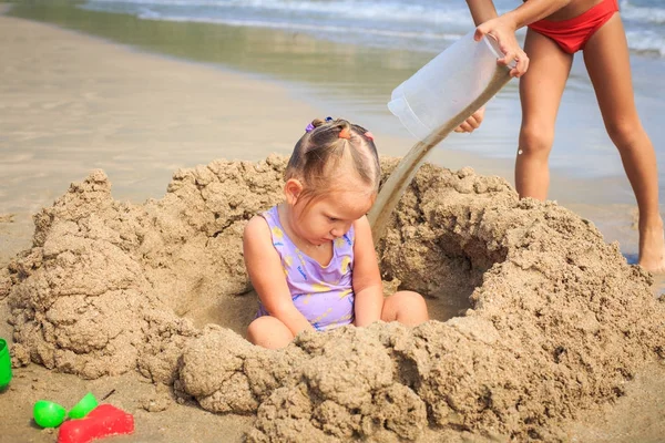 Sahilde kum yığını arasında kız oturur
