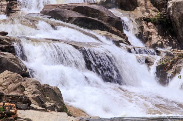 茶色の石の間で泡沫山川滝のカスケードをクローズ アップ — ストック写真